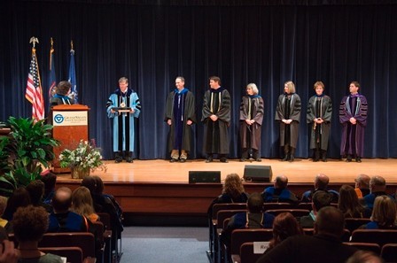 Gayle Davis, Tom Haas and faculty stand on stage